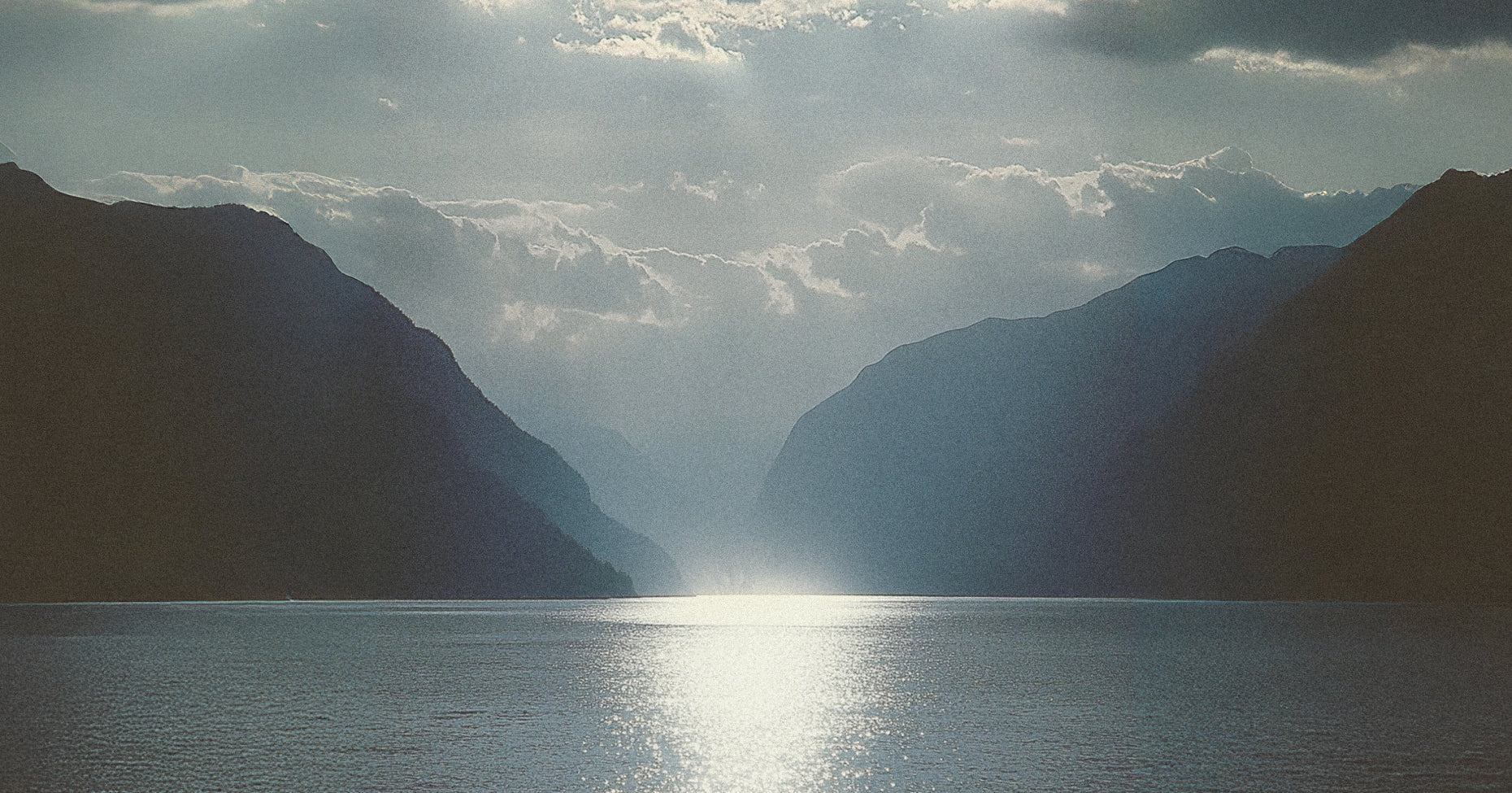 Mountainous landscape with a body of water reflecting sunlight