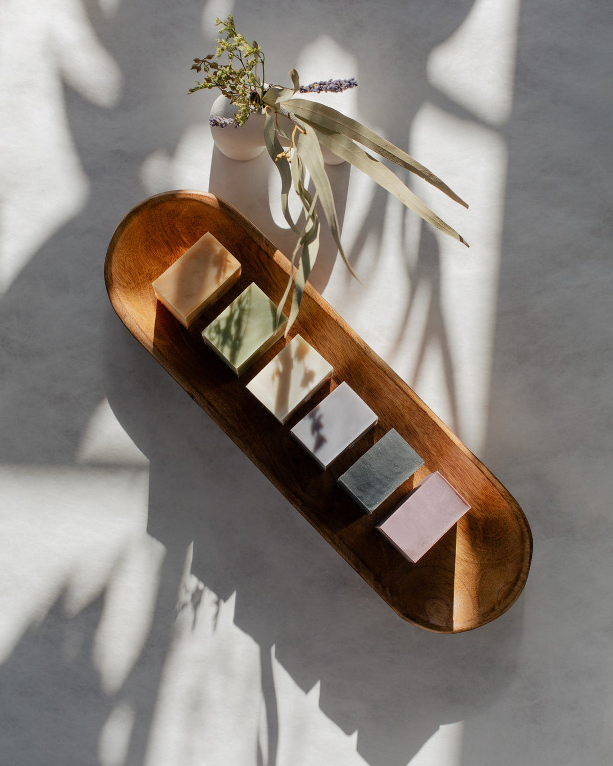 a set of 6 handmade natural soap bars on a top view sitting on a wooden tray.