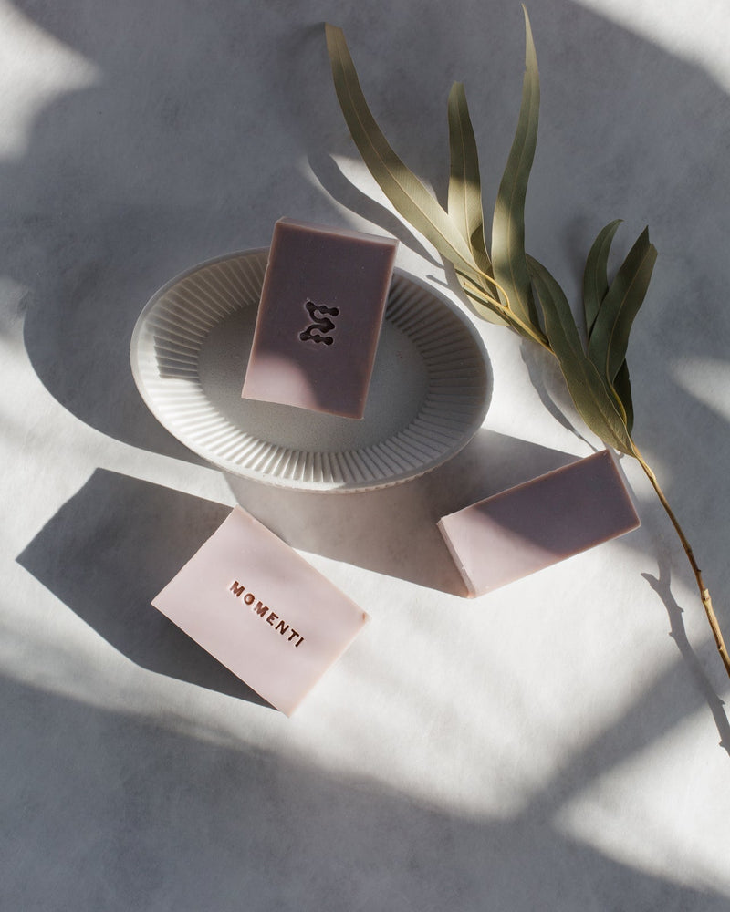 3 light purple handmade natural soap bars on a white background with eucalyptus leaves.