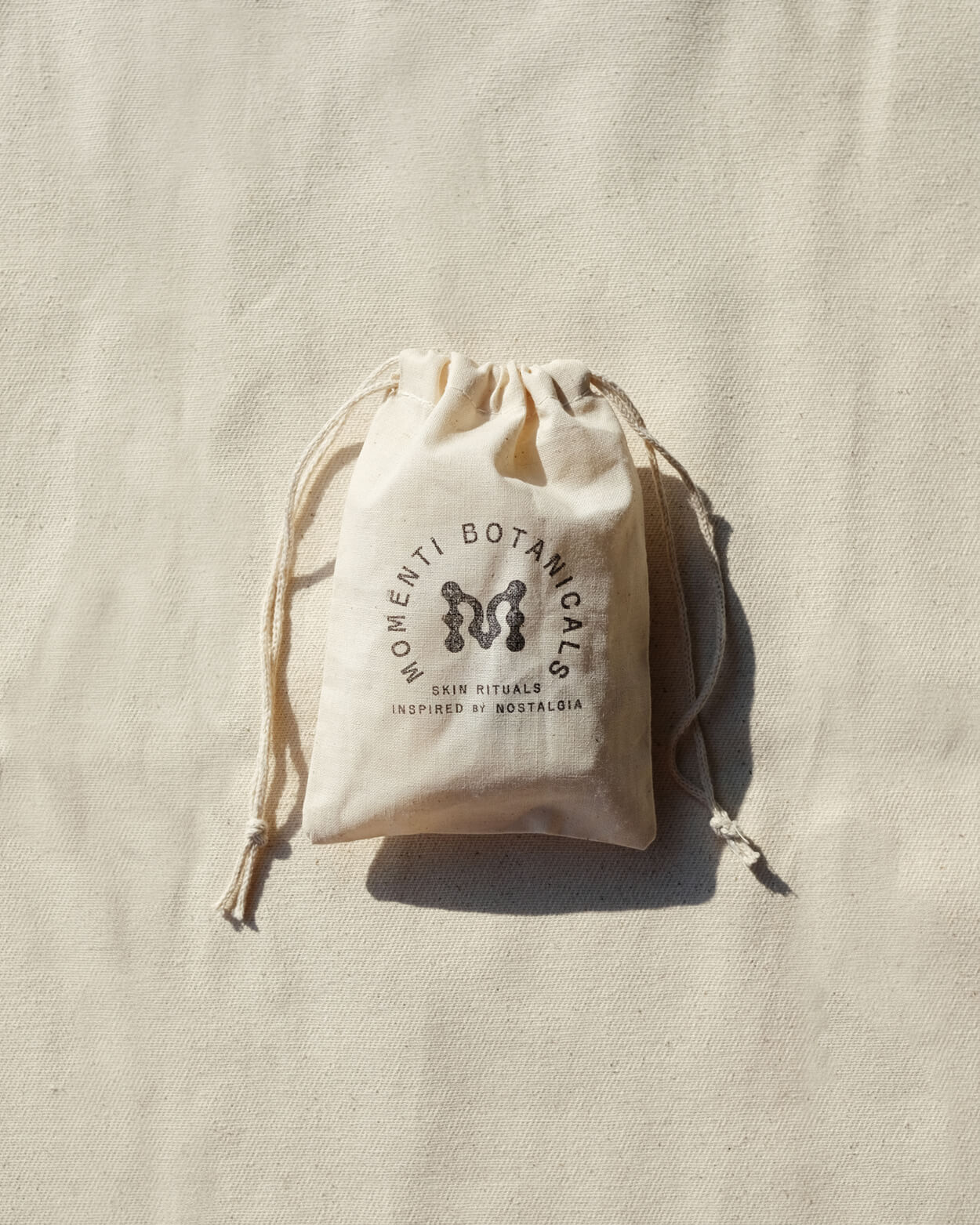 Organic Cotton Gift Bag with the Momenti Botanicals crest stamped on the front of the bag