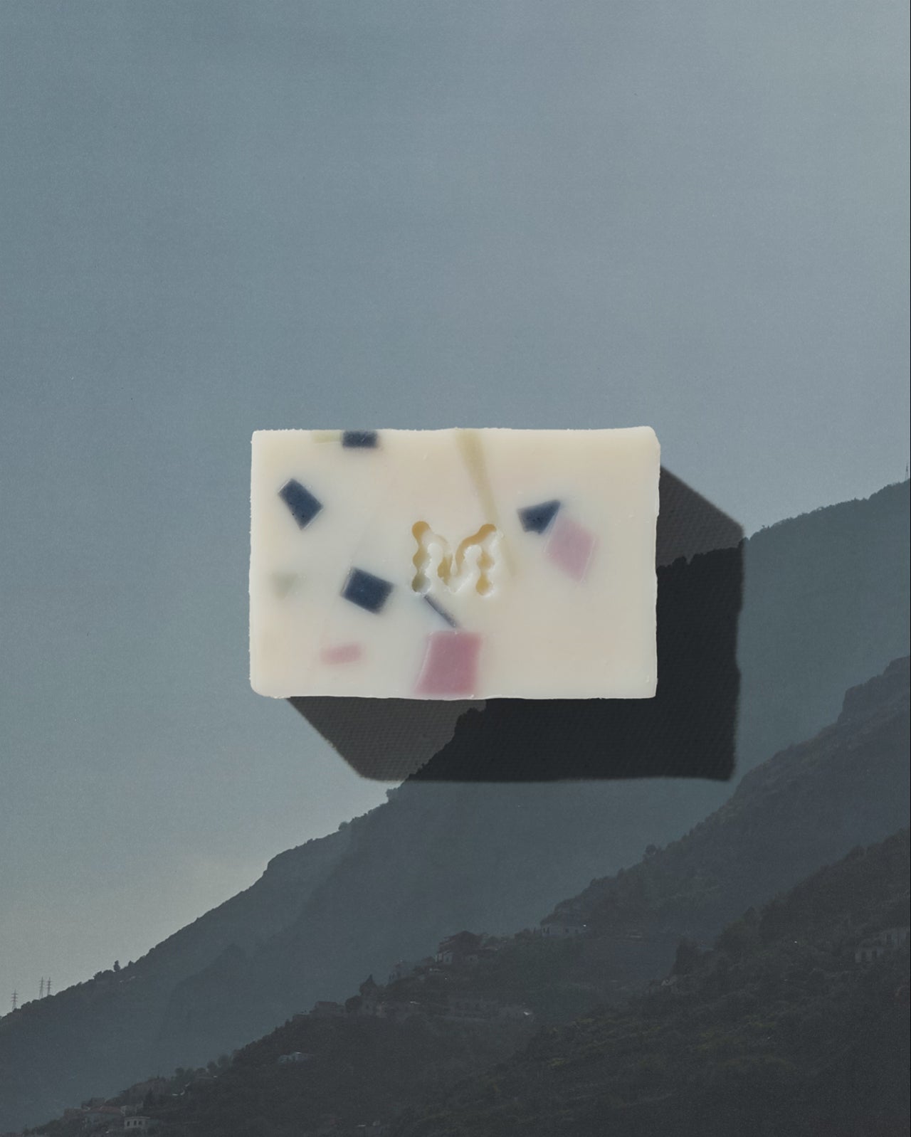 Natural speckled soaps on an alternating background featuring scenes from the Amalfi Coast